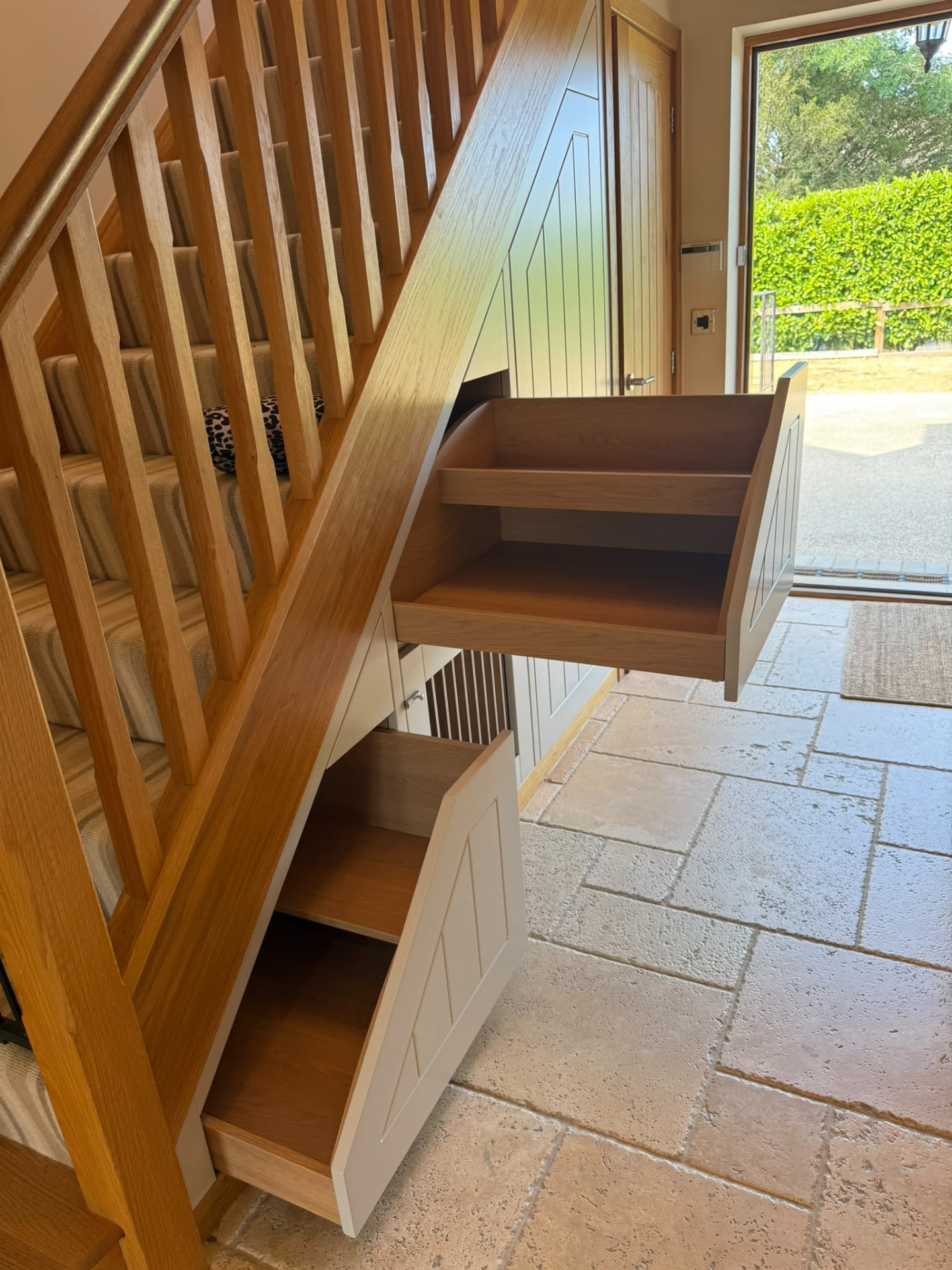 Bespoke painted pull-out storage with oak interiors beneath a staircase